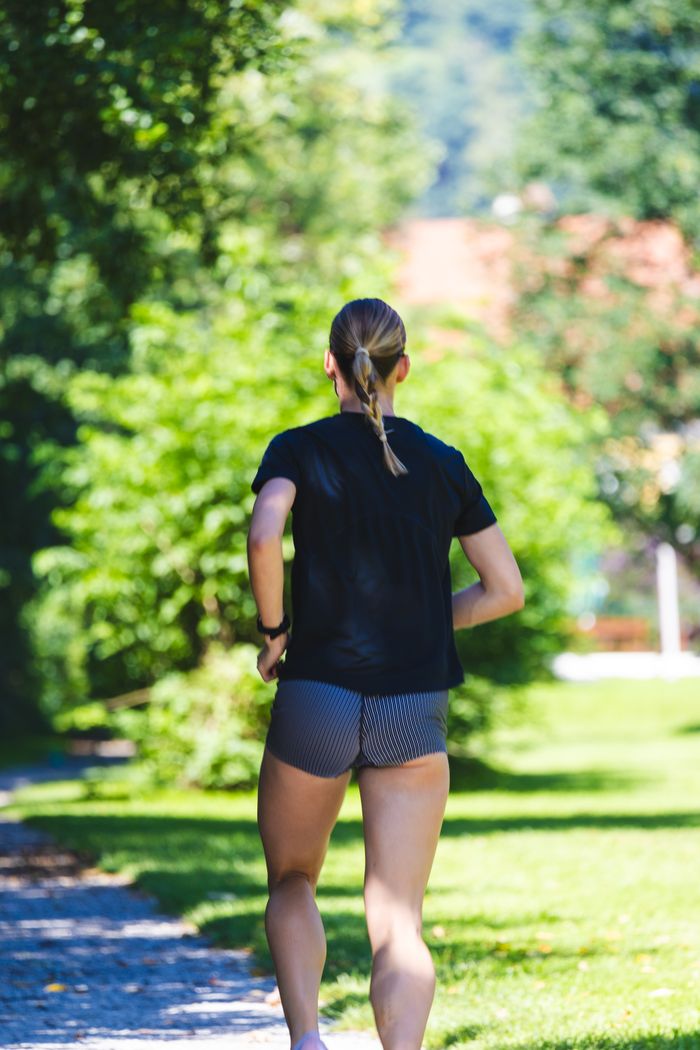 The Art of Drawing Readers In: Your attractive post title goes here Back view of a woman jogging on a sunny day in a lush green park, embodying healthy lifestyle.
